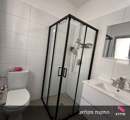 מקלחון זכוכית עם דלתות שחורות ומדף מתכת